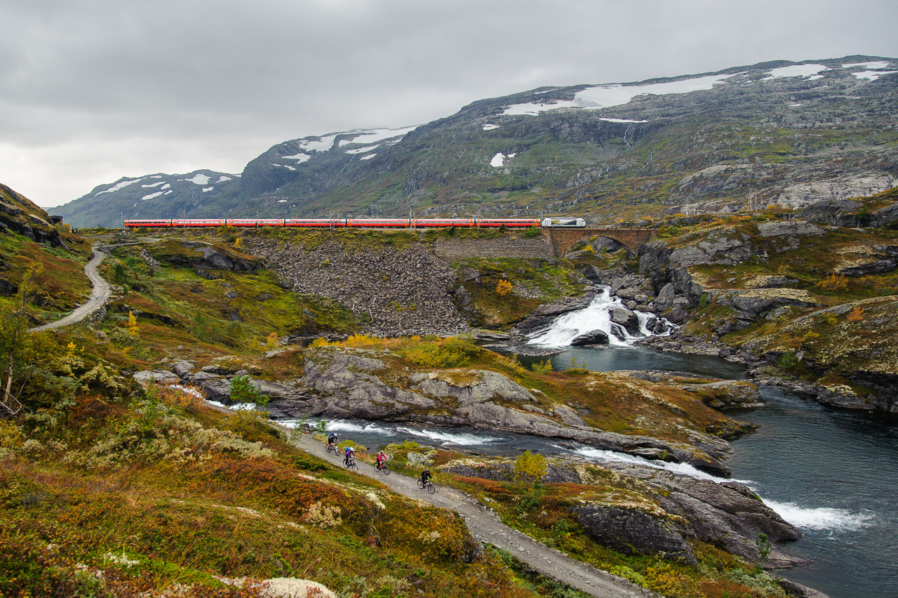 Kleva bridge, a masterpiece of 1910 engineering. Train 601 crosses the bridge while a pair of bicycle touristes has started the decent towards Flåm. The old navi road is a popular route during the short summer.
